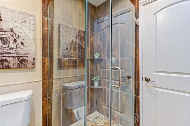 bathroom featuring a shower with shower door and toilet