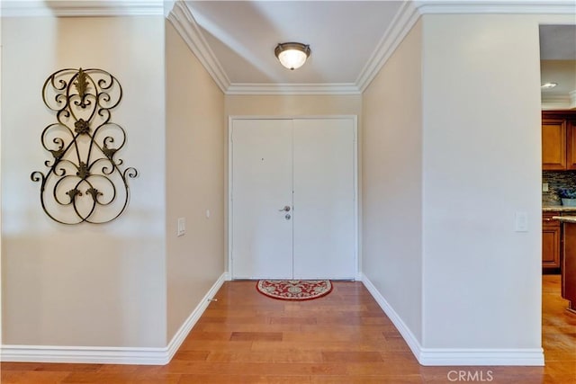 entryway featuring ornamental molding and light hardwood / wood-style floors