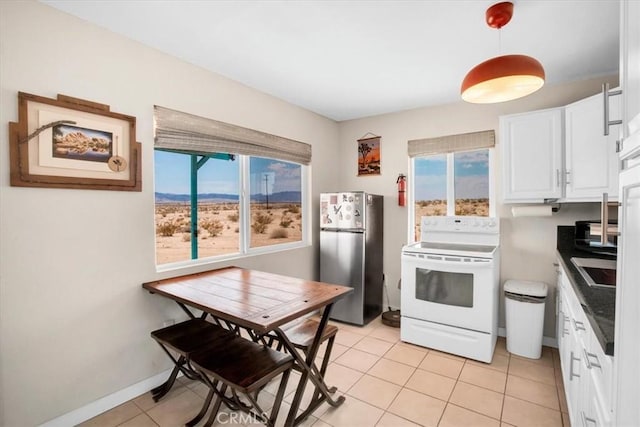 kitchen featuring decorative light fixtures, white range with electric stovetop, stainless steel refrigerator, white cabinetry, and light tile patterned floors