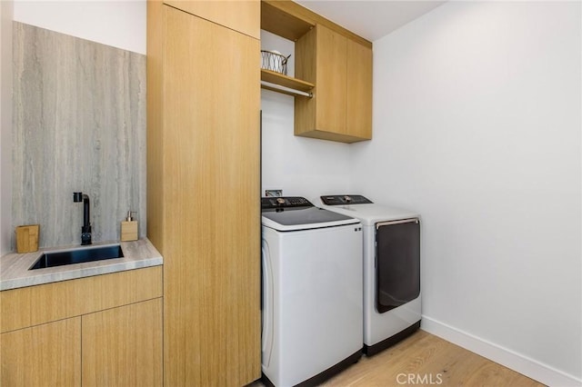 laundry area with cabinets, sink, light wood-type flooring, and washing machine and clothes dryer