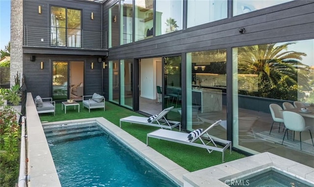 rear view of property with a pool with hot tub, a pergola, a balcony, and a patio