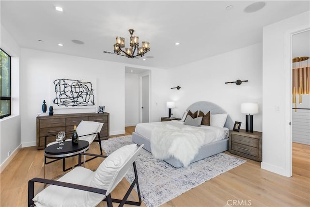 bedroom featuring ensuite bath, light hardwood / wood-style flooring, and a notable chandelier