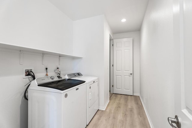 laundry area with light hardwood / wood-style flooring and washing machine and clothes dryer