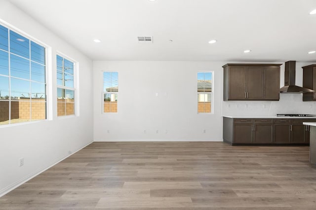 kitchen featuring light hardwood / wood-style floors, wall chimney exhaust hood, gas stovetop, and dark brown cabinetry