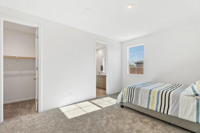 bedroom with light carpet, a closet, a spacious closet, and connected bathroom