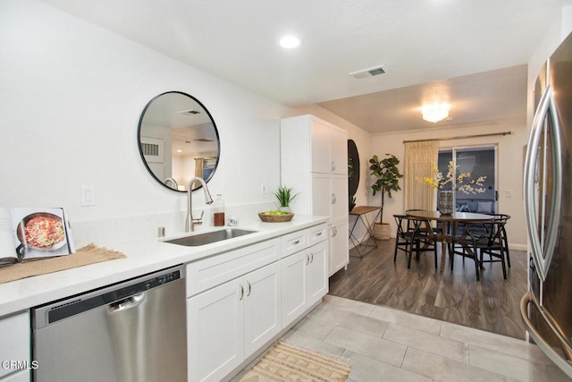 kitchen featuring light tile patterned floors, appliances with stainless steel finishes, white cabinetry, and sink