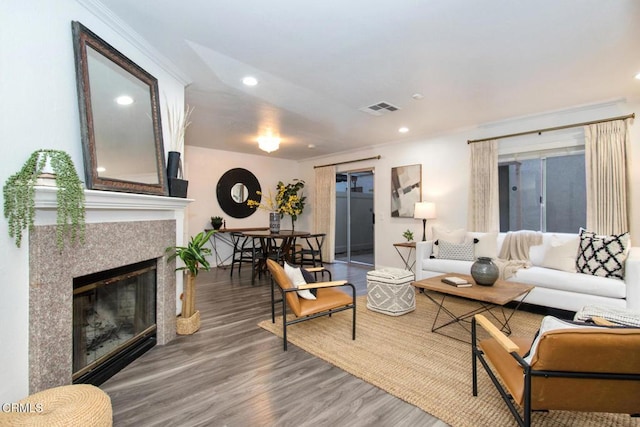 living room featuring crown molding, hardwood / wood-style floors, and a tile fireplace