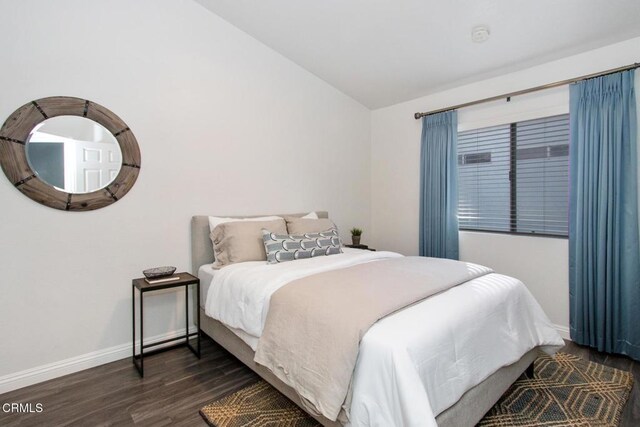 bedroom featuring dark wood-type flooring and vaulted ceiling