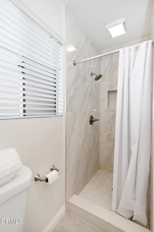 bathroom with toilet and a shower with shower curtain