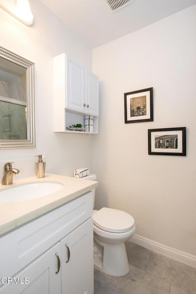 bathroom featuring toilet, vanity, tile patterned flooring, and a shower with shower door