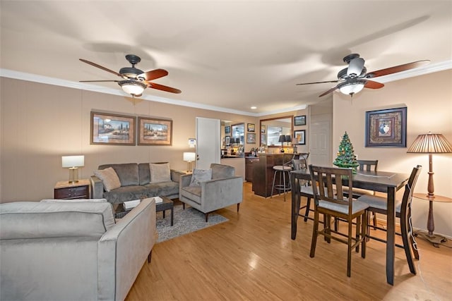 living room with ceiling fan, crown molding, and light hardwood / wood-style flooring