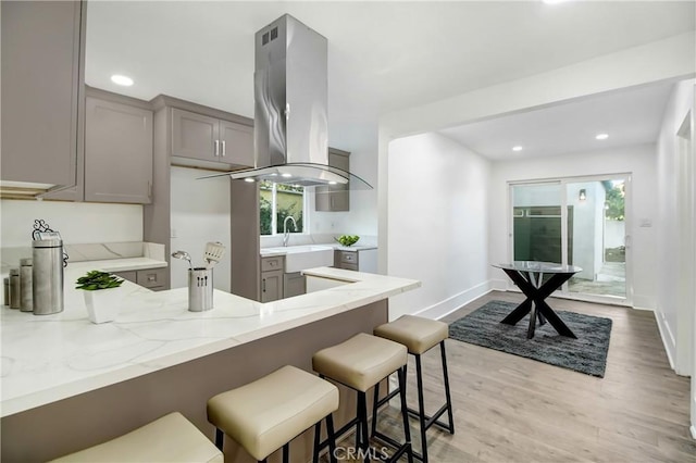 5737 5th, Los Angeles, CA 90043 - kitchen featuring gray cabinets, a breakfast bar, light stone countertops, a peninsula, and light wood-type flooring