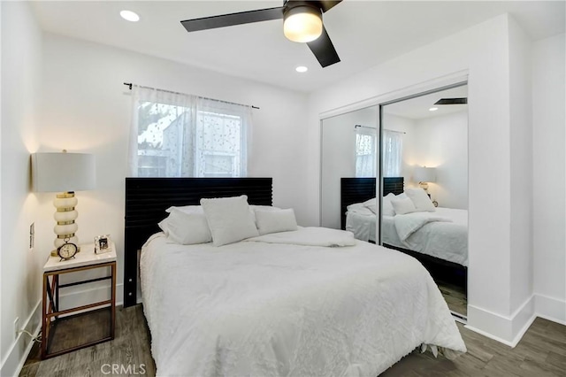 bedroom with ceiling fan, dark wood-type flooring, multiple windows, and a closet