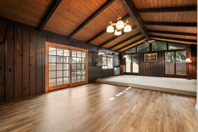 unfurnished living room with wood ceiling, wood walls, and lofted ceiling with beams