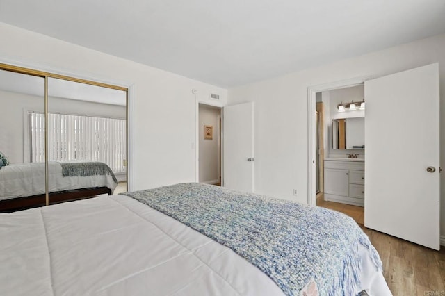 bedroom with a closet, connected bathroom, and light hardwood / wood-style flooring