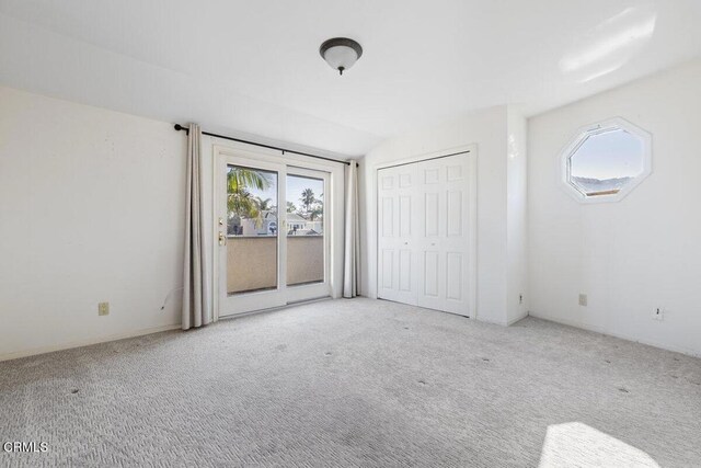 unfurnished bedroom featuring lofted ceiling, light colored carpet, and multiple windows