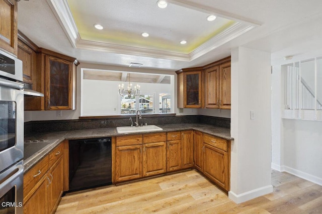 kitchen with a sink, a tray ceiling, black appliances, and crown molding