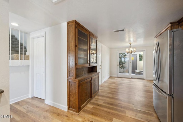 kitchen with visible vents, glass insert cabinets, a notable chandelier, freestanding refrigerator, and light wood finished floors