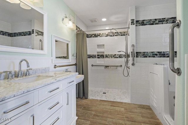bathroom with visible vents, a tile shower, vanity, and wood finished floors
