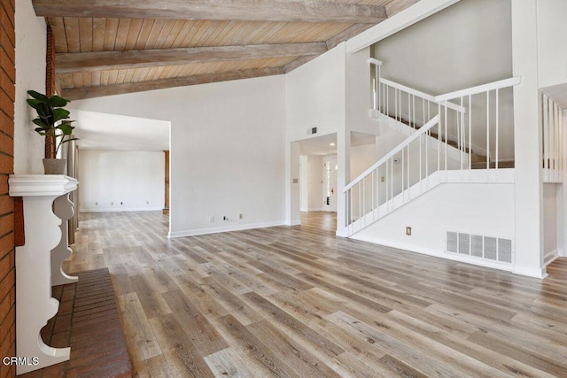 unfurnished living room featuring visible vents, wood ceiling, beamed ceiling, stairway, and wood finished floors