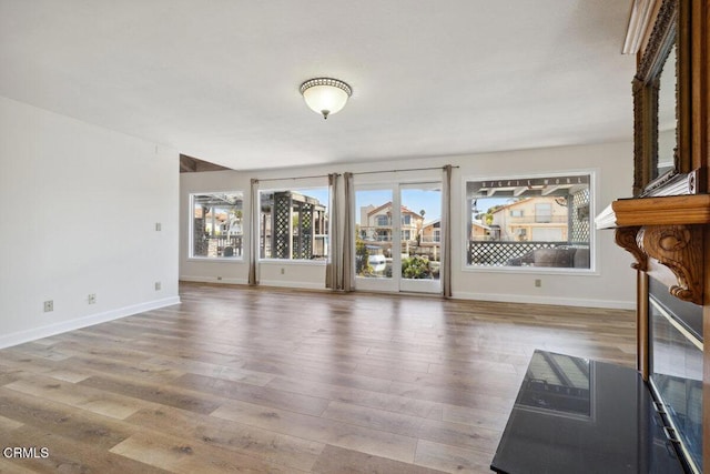 unfurnished living room featuring wood finished floors and baseboards