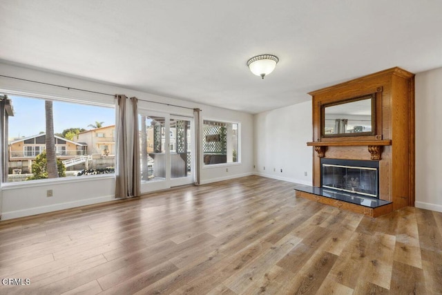 unfurnished living room with wood finished floors, a fireplace, and baseboards