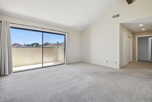carpeted spare room with visible vents, vaulted ceiling, and a textured ceiling