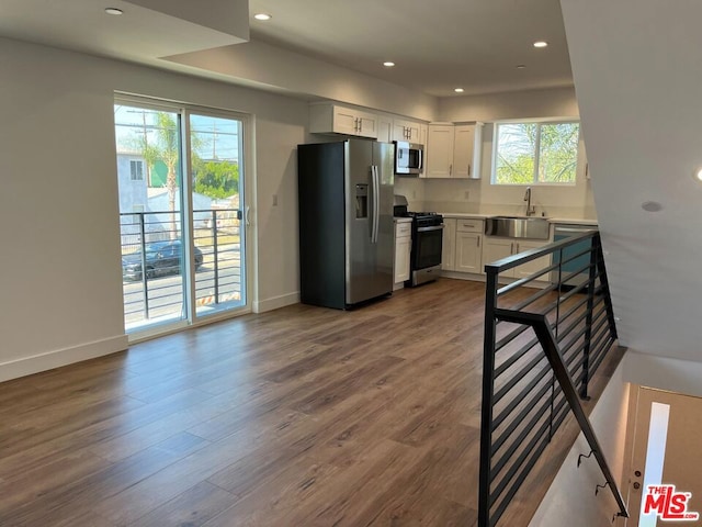 kitchen with sink, hardwood / wood-style floors, white cabinets, and stainless steel appliances