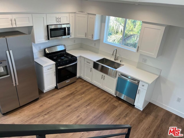 kitchen featuring sink, hardwood / wood-style flooring, stainless steel appliances, and white cabinetry