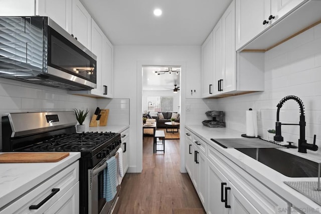 kitchen featuring white cabinets, appliances with stainless steel finishes, dark hardwood / wood-style flooring, sink, and ceiling fan