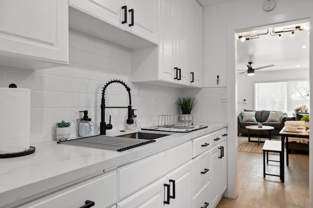 kitchen featuring ceiling fan, light stone counters, white cabinetry, and tasteful backsplash