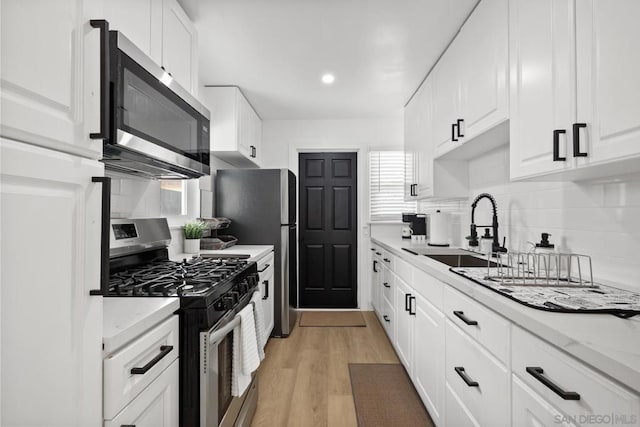 kitchen featuring light stone countertops, stainless steel appliances, white cabinetry, and sink