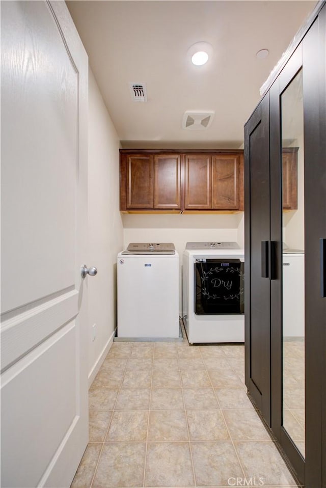 washroom featuring cabinet space, light tile patterned flooring, visible vents, and washing machine and clothes dryer