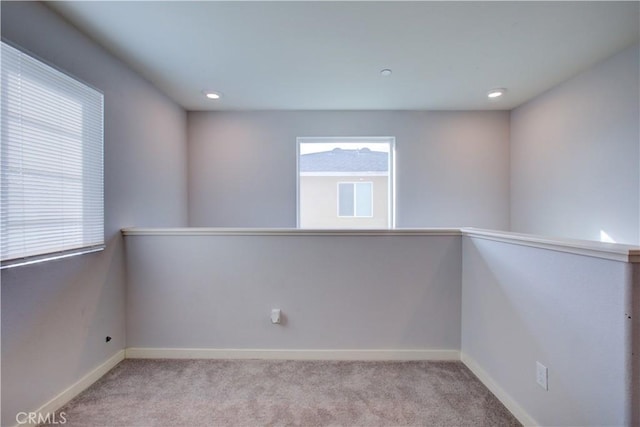 spare room featuring light carpet, recessed lighting, and baseboards