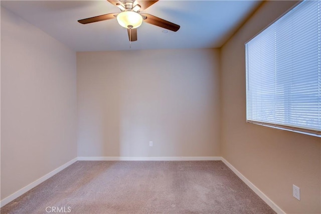 empty room featuring light carpet, a ceiling fan, and baseboards