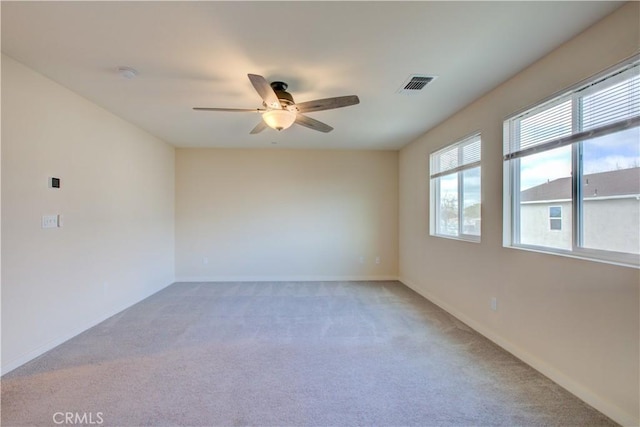 carpeted spare room featuring ceiling fan, visible vents, and baseboards