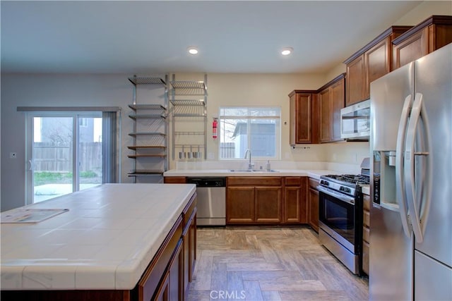 kitchen with brown cabinets, stainless steel appliances, a sink, and recessed lighting