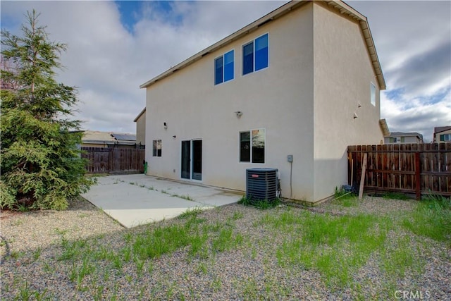 rear view of house with a patio, central AC, a fenced backyard, and stucco siding