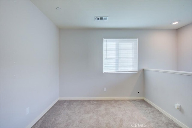 unfurnished room with light colored carpet, visible vents, and baseboards