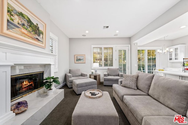 living room with dark colored carpet, a notable chandelier, and a fireplace