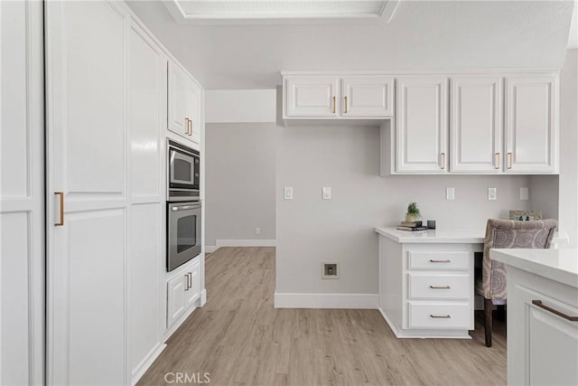 kitchen featuring built in desk, stainless steel oven, white cabinets, and built in microwave