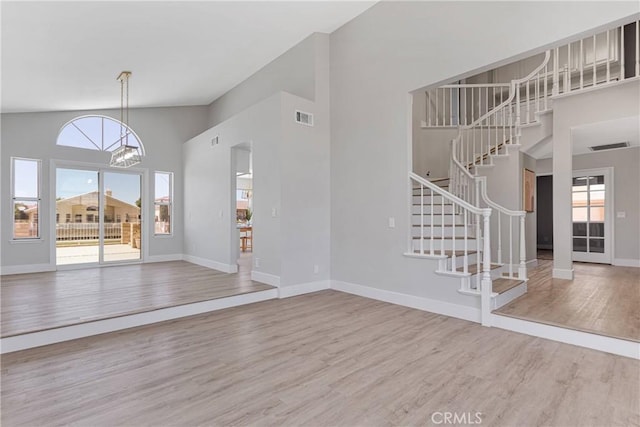 unfurnished living room with a chandelier, hardwood / wood-style flooring, and high vaulted ceiling