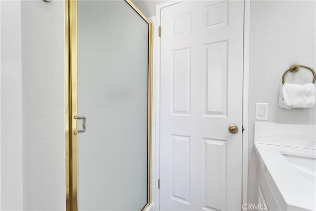 bathroom featuring a shower with door and vanity