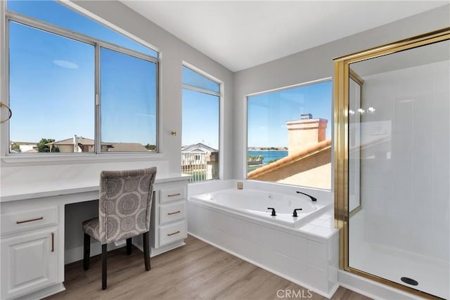 bathroom with plenty of natural light, hardwood / wood-style floors, a water view, and shower with separate bathtub