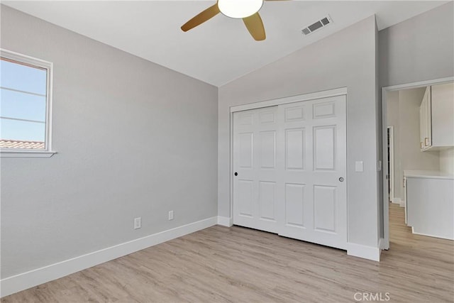 unfurnished bedroom with a closet, lofted ceiling, light hardwood / wood-style flooring, and ceiling fan