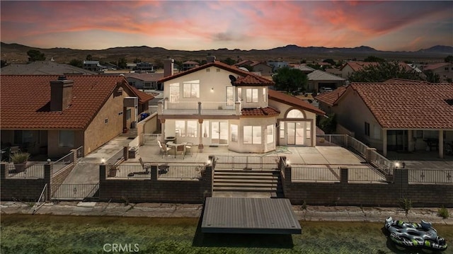 back house at dusk with a mountain view and a patio