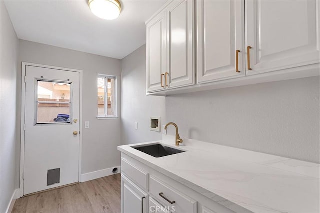 laundry room featuring cabinets, sink, hookup for a washing machine, and light wood-type flooring