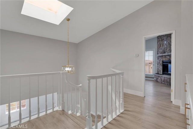 stairs featuring wood-type flooring, a skylight, and a stone fireplace