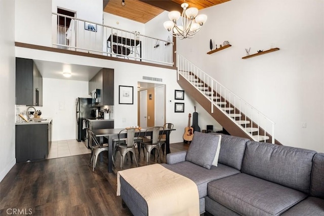 living room featuring wood-type flooring, wood ceiling, a high ceiling, and a notable chandelier