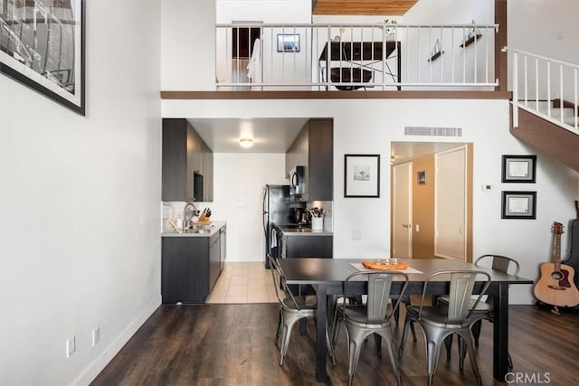 dining room featuring hardwood / wood-style flooring, sink, and a towering ceiling